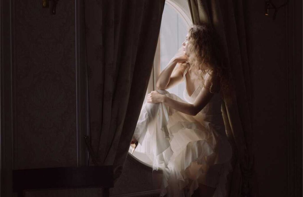 Lekcije o životu: 14 moćnih istina za unutarnji mir i mudrost Žena sjedi na prozoru i gleda van dok razmišlja o tome koje su najvažnije lekcije o životu