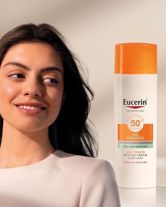 Eucerin Oil Control SPF 50+ Sun Gel-Cream u prepoznatljivom bijelom pakiranju s narančastim čepom, prikazan uz portret žene s čistom i matiranom kožom, namijenjen zaštiti masne kože sklone aknama.