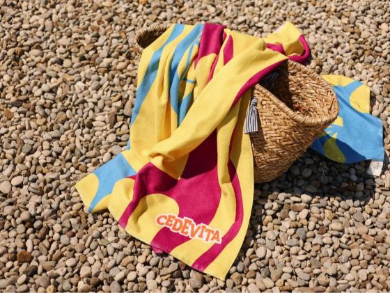 Cedevita i moje more ručnici stavljeni preko torbe za plažu.