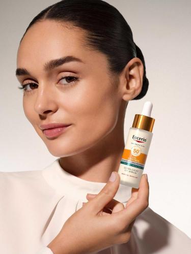 Žena drži u ruci Eucerin Oil Control UV serum SPF50.