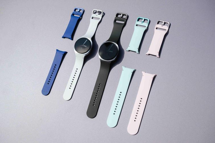 Samsung Galaxy Watch pametni satovi u bijeloj i crnoj boji s dodatnim zamjenjivim remenima u plavoj, tirkiznoj i ružičastoj boji na sivoj pozadini.