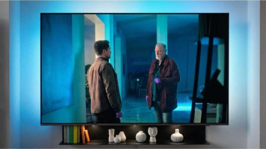 Pogledali smo skandinavski mračni dragulj koji osvaja od prve minute Scena iz serije Blood sacrifice na modernom televizoru, prikazuje glavne likove u plavoj prostoriji s pozadinskim osvjetljenjem.