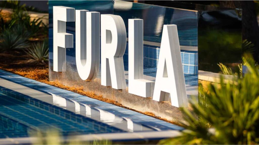 Furla Beach Club Experience: Večer talijanskog dizajna u Poreču Veliki bijeli logo Furla uz bazen u sklopu Furla Beach Club Experience događaja u Purobeachu Poreč.