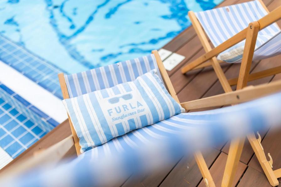 Pogled odozgo na personalizirane ležaljke s logotipom 'Furla Sunglasses Bar' uz bazen.