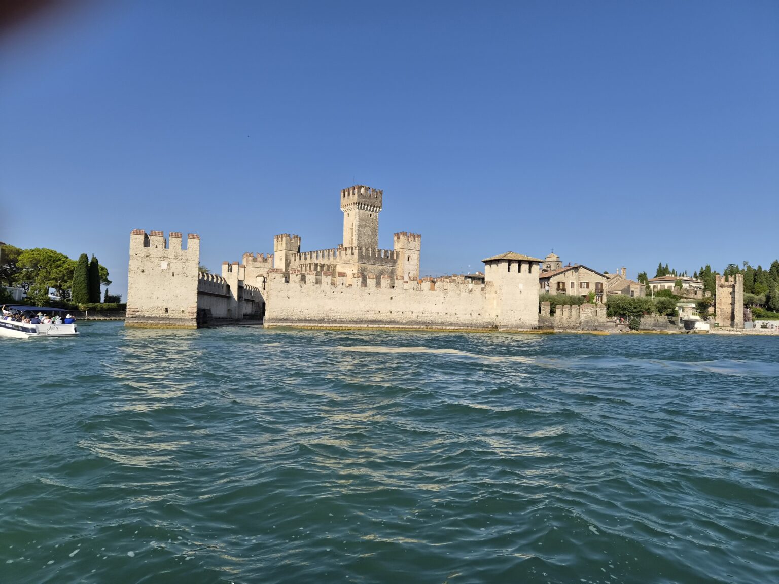 Sirmione jezero Garda: Talijanski gradić u kojem se lako zaljubiti u život Sirmione jezero Garda, srednjovjekovni dvorac Castello Scaligero okružen tirkiznom vodom pod vedrim nebom
