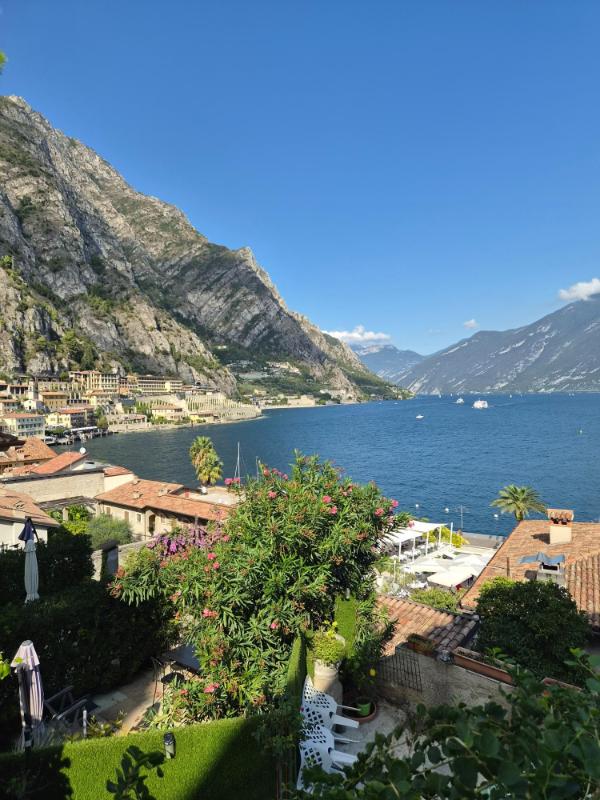 Panoramski pogled s povišenog dijela grada Limone sul Garda na tirkizno jezero, krovove kuća i strme alpske litice.