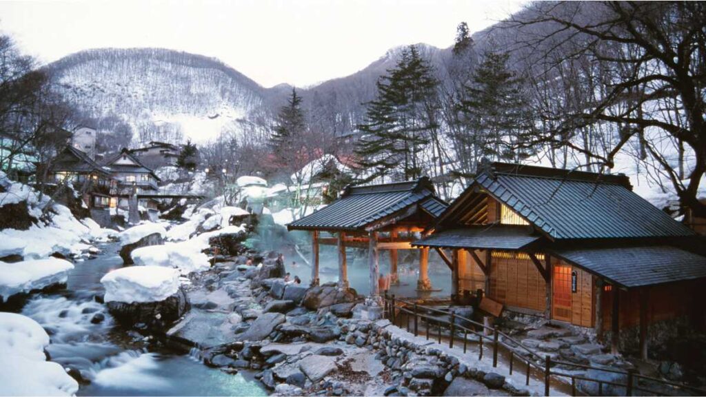 Zimski pejzaž japanskog ryokana Takaragawa Onsen Ousenkaku s vanjskim termalnim kupkama uz rijeku, okružen snijegom i tradicionalnom drvenom arhitekturom. Ovakvi neobični smještaji za odmor pružaju autentičan doživljaj destinacije.