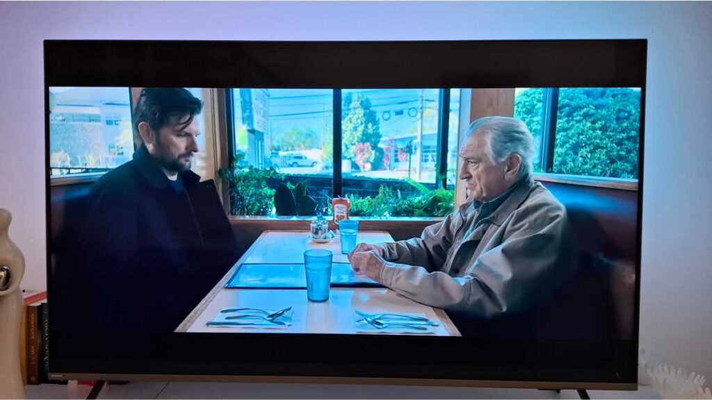 5 novih trilera na Netflixu: Koji vrijede vašeg vremena, a koje preskočiti? Novi trileri na Netflixu: Prikaz televizijskog ekrana na kojem glumci Adam Scott i Robert De Niro sjede jedan nasuprot drugome za stolom u restoranu, u sceni iz Netflixovog trilera Šaptač.