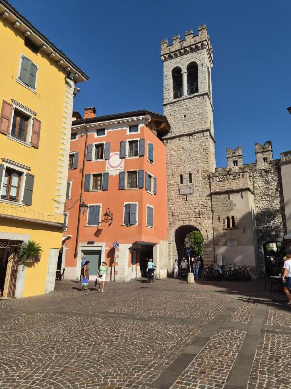 Srednjovjekovna gradska vrata Porta San Michele i kameni toranj sa šarenim zgradama u staroj jezgri Riva del Garde.