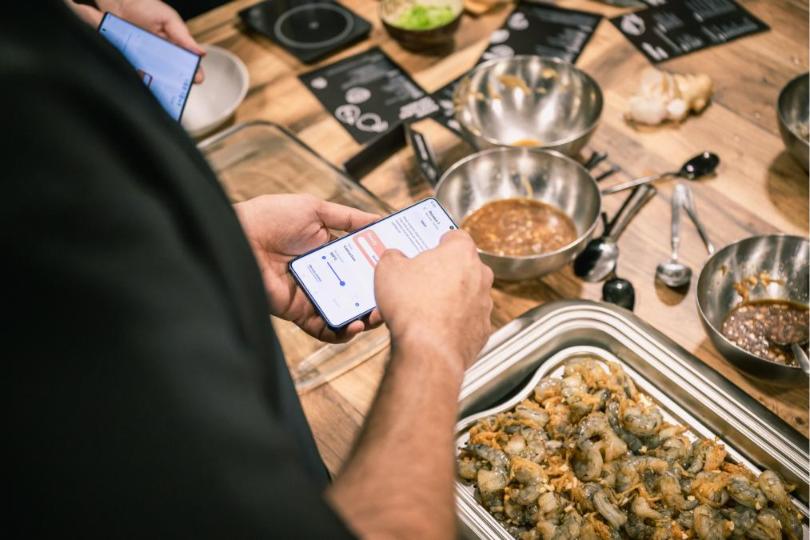 Korištenje SmartThings aplikacije na pametnom telefonu za upravljanje dok Samsung kućanski uređaji olakšavaju pripremu hrane.