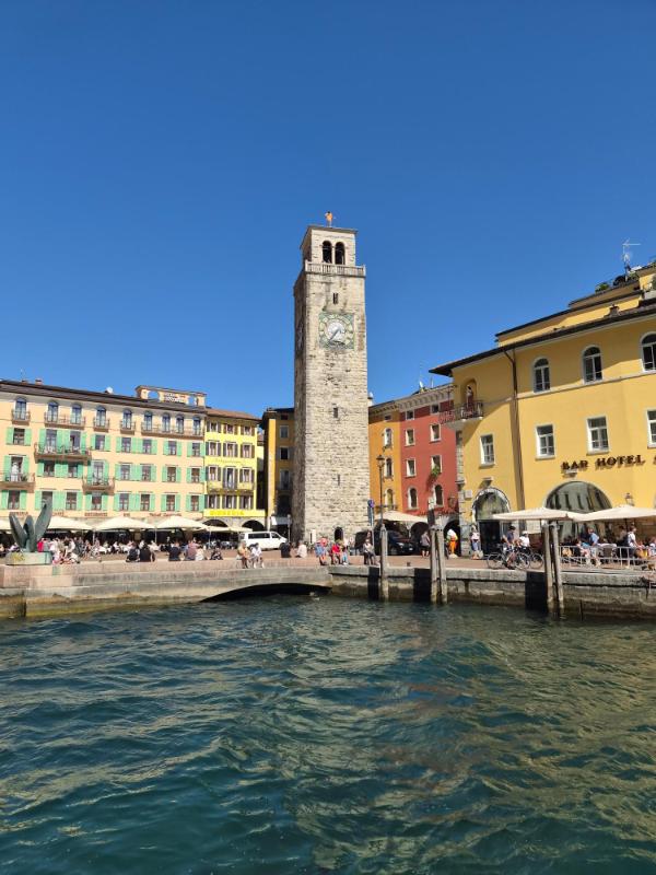 Srednjovjekovni toranj Torre Apponale i šarene zgrade na obali luke u gradu Riva del Garda na jezeru Garda.